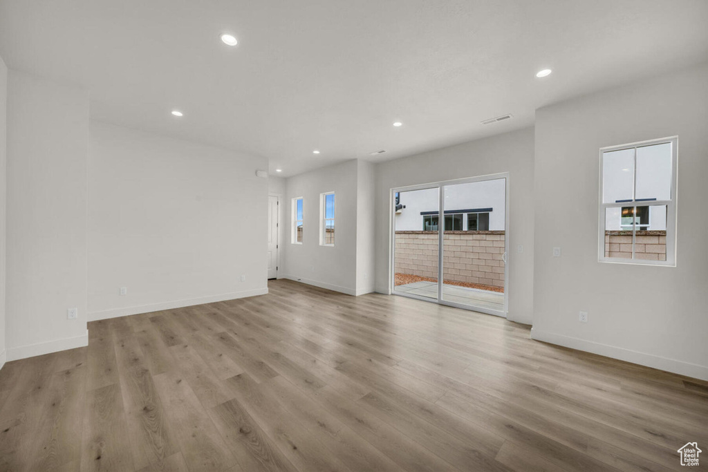 Unfurnished living room with light hardwood / wood-style floors and a healthy amount of sunlight