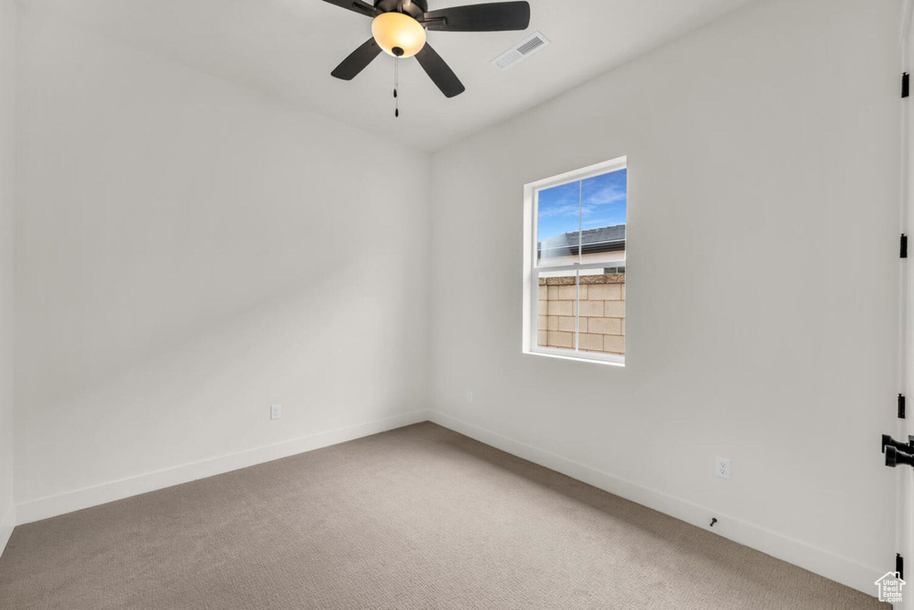 Carpeted spare room featuring ceiling fan