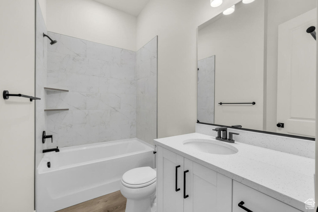 Full bathroom featuring vanity, tiled shower / bath combo, wood-type flooring, and toilet