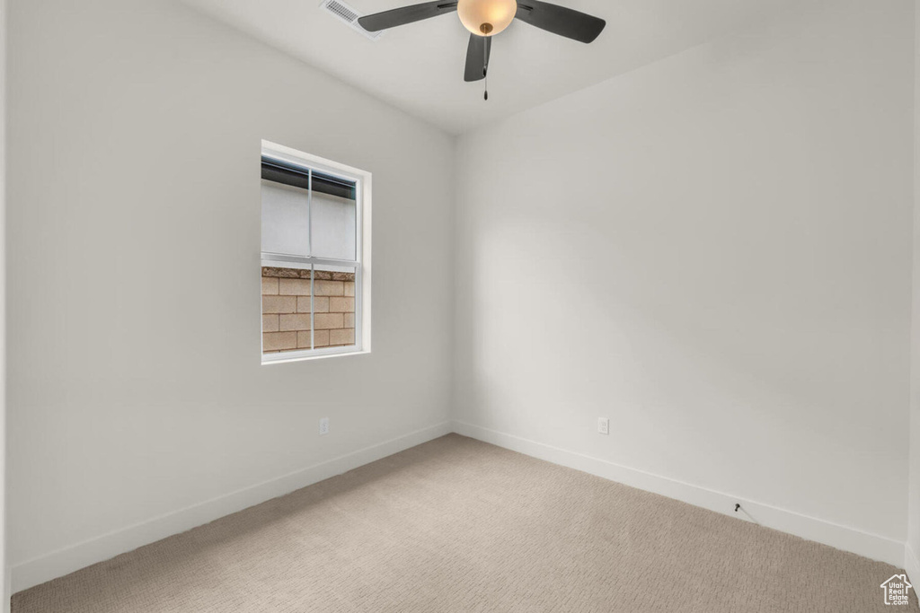 Carpeted spare room featuring ceiling fan