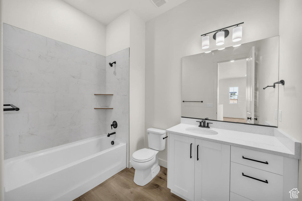 Full bathroom featuring wood-type flooring, toilet, vanity, and tiled shower / bath