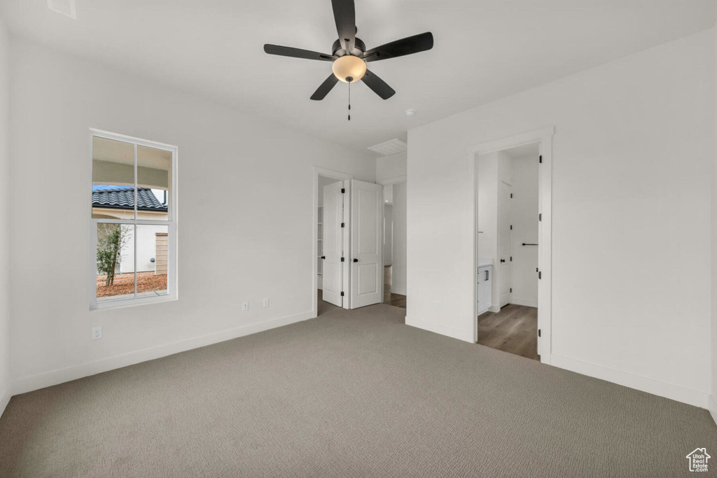 Unfurnished bedroom featuring carpet flooring, ensuite bath, and ceiling fan