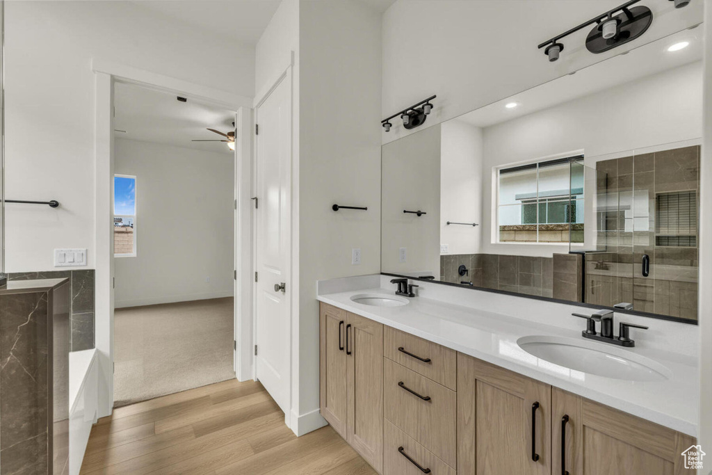 Bathroom featuring ceiling fan, independent shower and bath, wood-type flooring, and dual bowl vanity