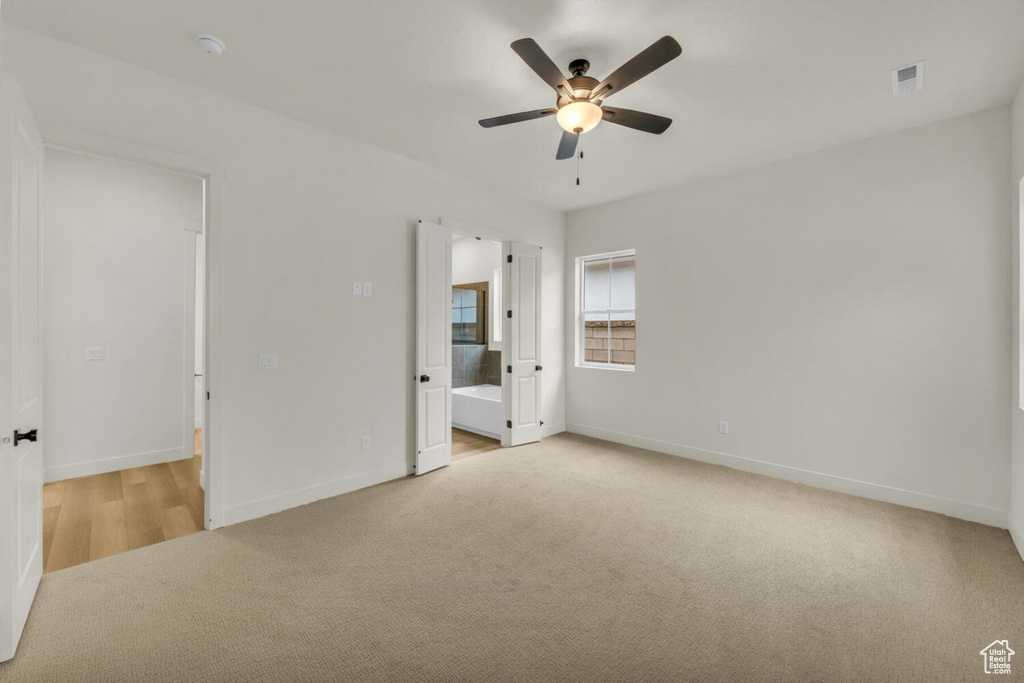 Unfurnished bedroom with ceiling fan, connected bathroom, and light colored carpet