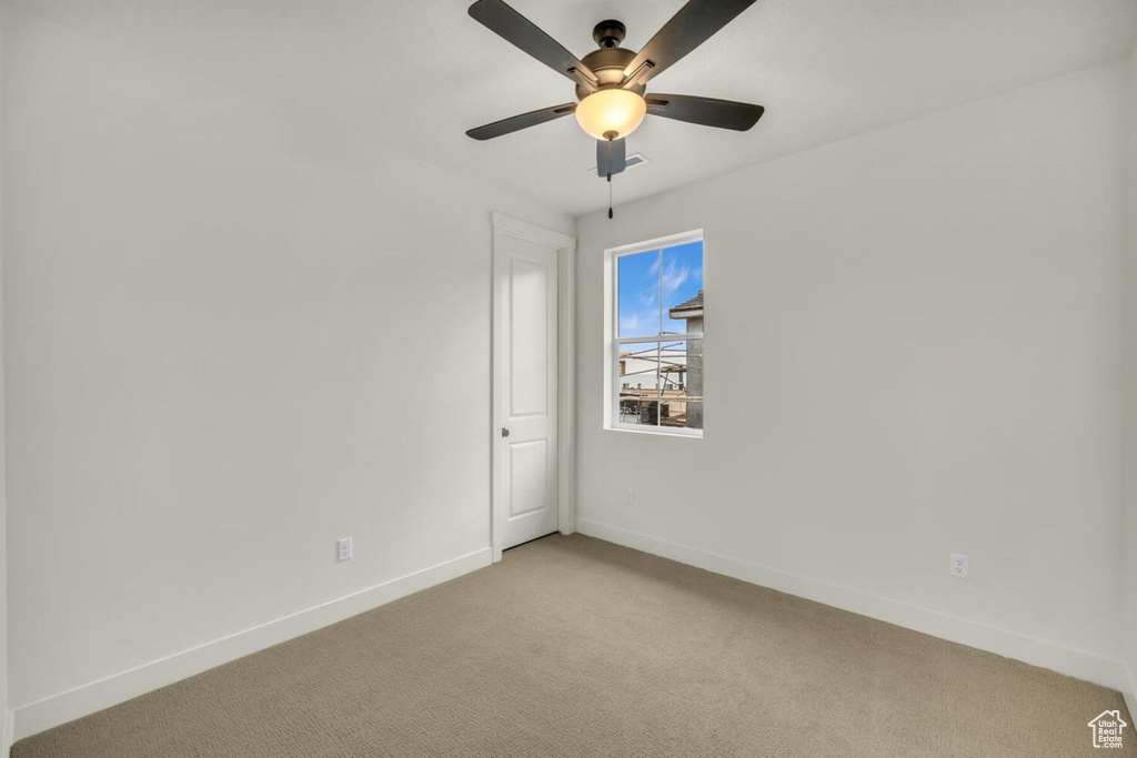 Empty room featuring light colored carpet and ceiling fan