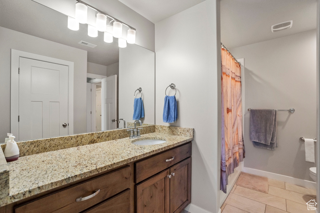 Bathroom with toilet, tile floors, and large vanity