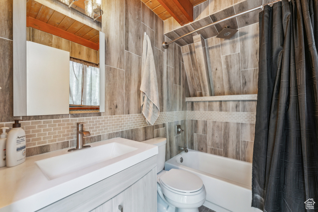 Full bathroom featuring vanity, shower / bathtub combination with curtain, tile walls, decorative backsplash, and toilet