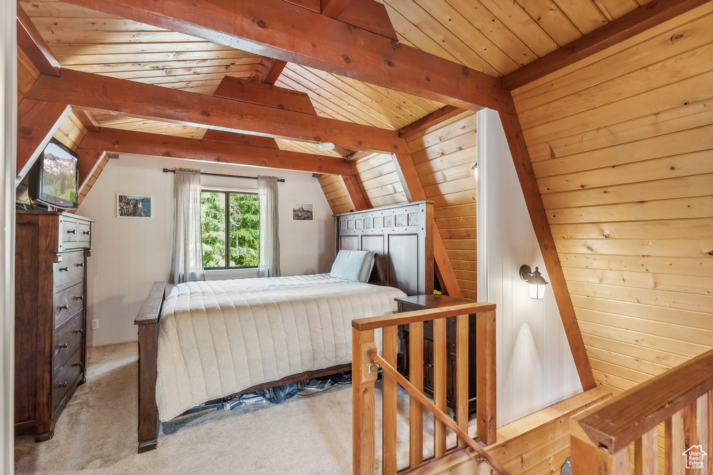 Carpeted bedroom with vaulted ceiling with beams, wood walls, and wooden ceiling