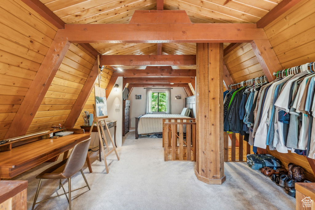 Walk in closet featuring vaulted ceiling with beams and light carpet