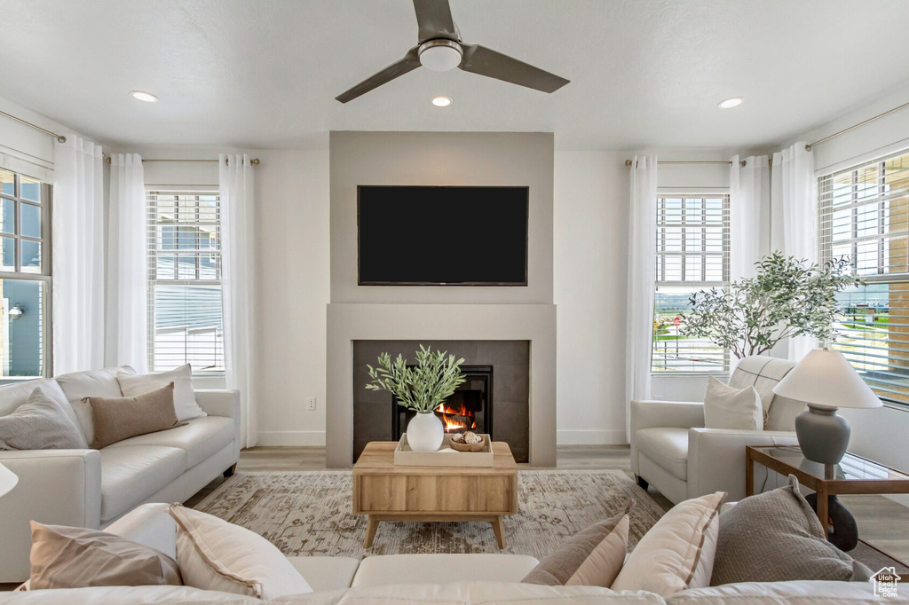 Living room with a tiled fireplace, ceiling fan, and hardwood / wood-style floors