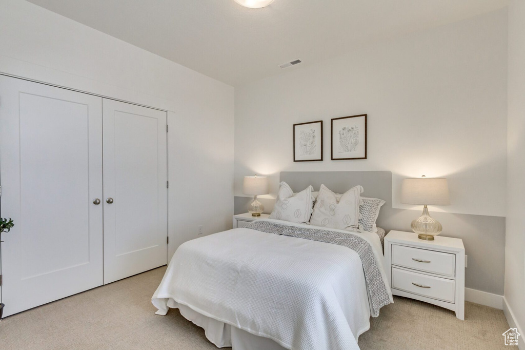 Bedroom with light colored carpet and a closet