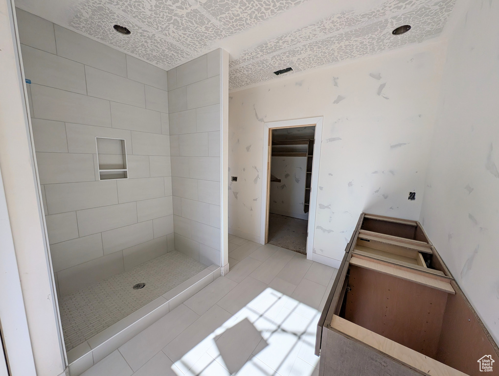 Bathroom with tile patterned floors and tiled shower