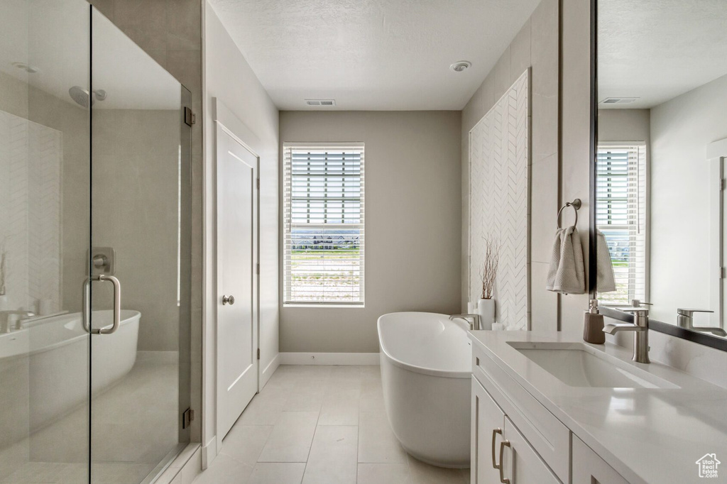 Bathroom with vanity, plus walk in shower, tile patterned flooring, and a textured ceiling