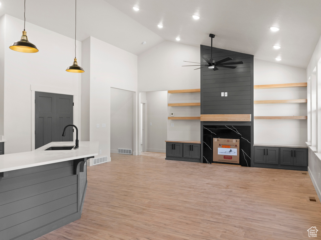 Living room featuring light wood-type flooring, high vaulted ceiling, sink, and ceiling fan