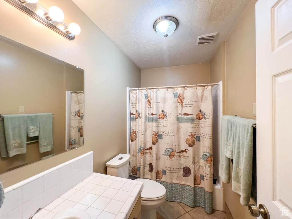 Bathroom with vanity, toilet, tile patterned floors, and a textured ceiling