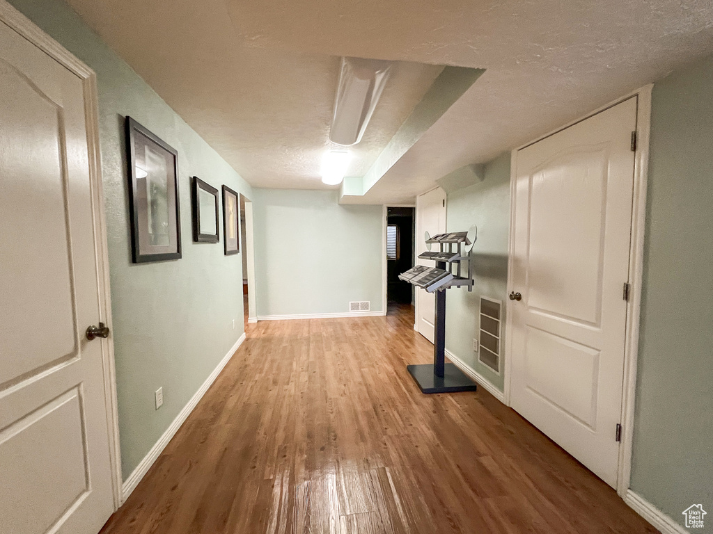 Corridor with light wood-type flooring and a textured ceiling