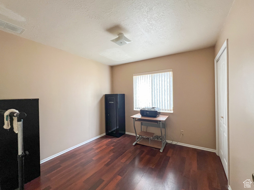 Misc room featuring dark wood-type flooring and a textured ceiling