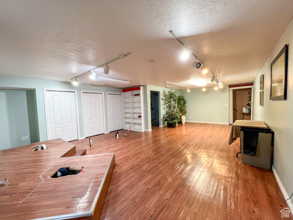 Interior space with a textured ceiling, wood-type flooring, and track lighting