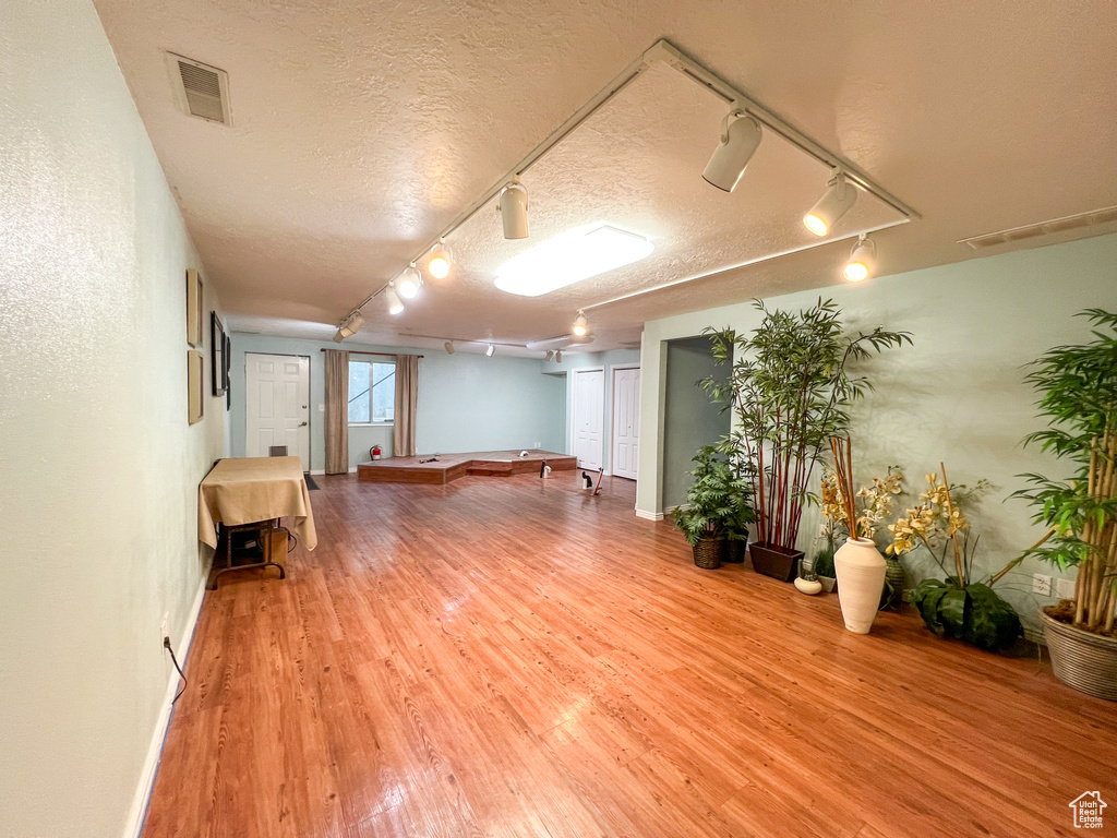 Basement featuring a textured ceiling, hardwood / wood-style floors, and track lighting