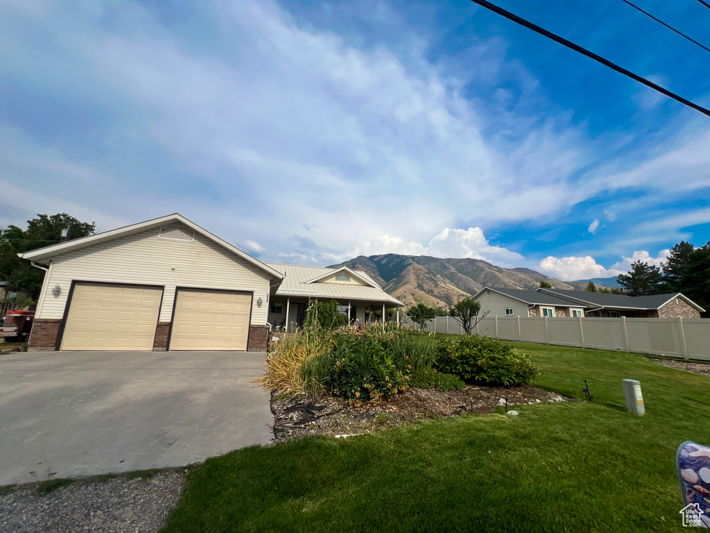 View of front of property featuring a garage, a front lawn, and a mountain view