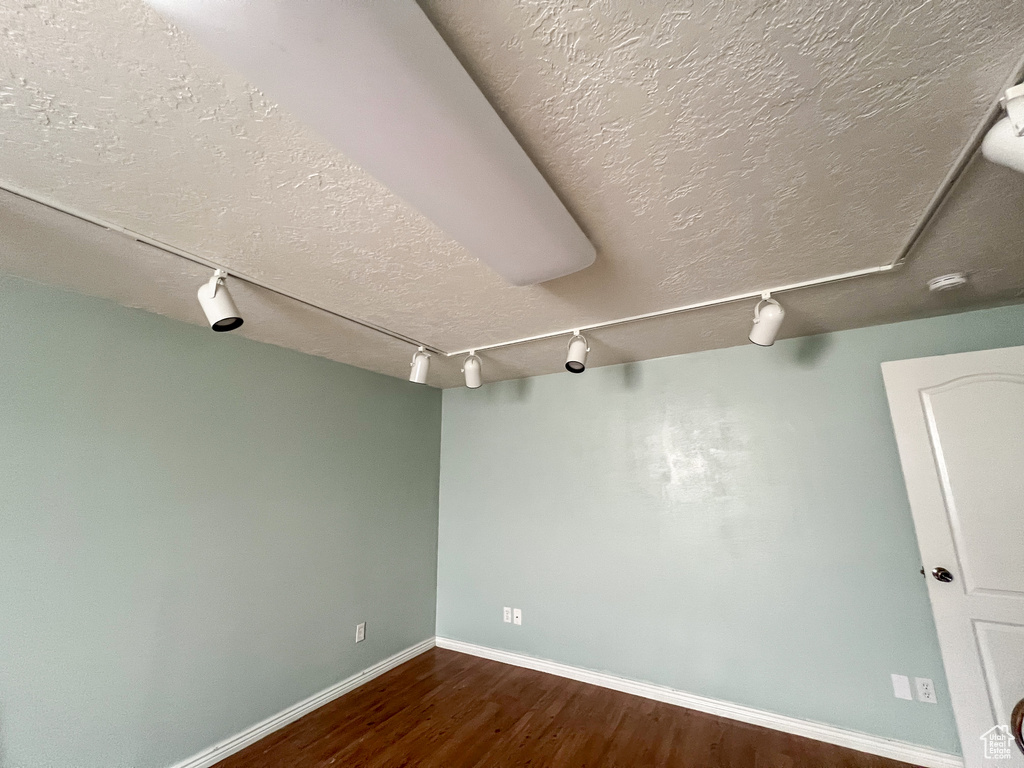 Empty room with a textured ceiling and wood-type flooring