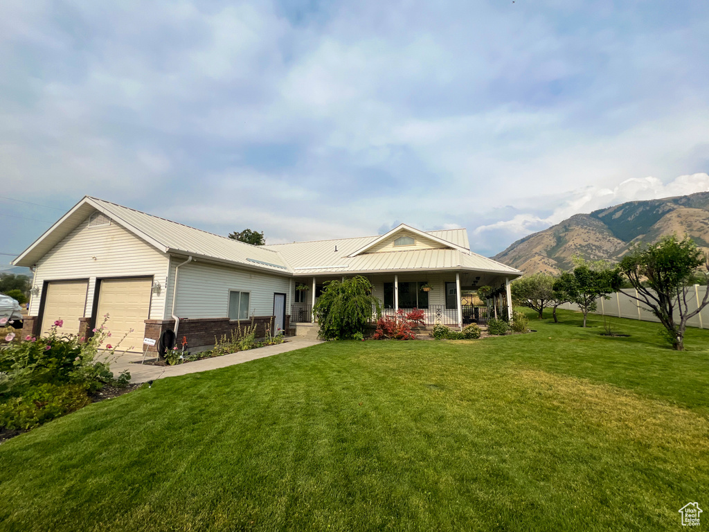 View of front facade with a mountain view, a porch, a garage, and a front lawn