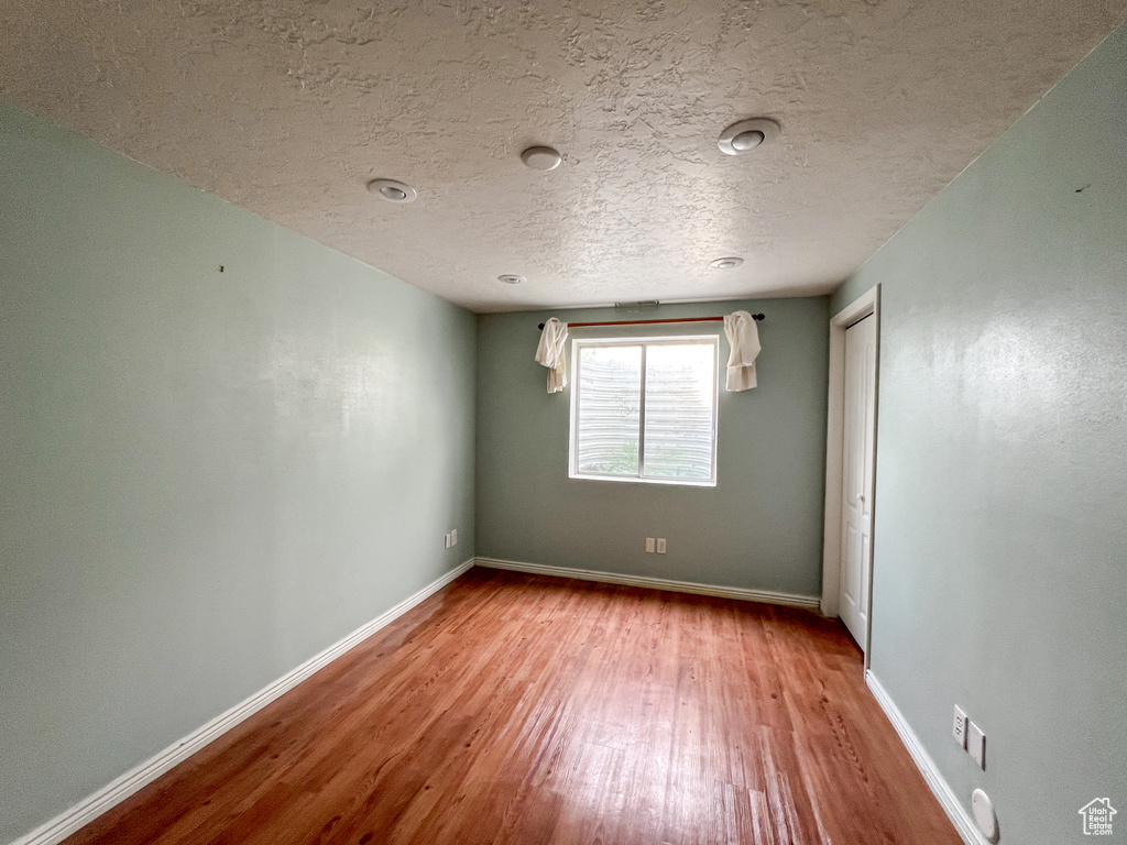 Empty room with a textured ceiling and wood-type flooring