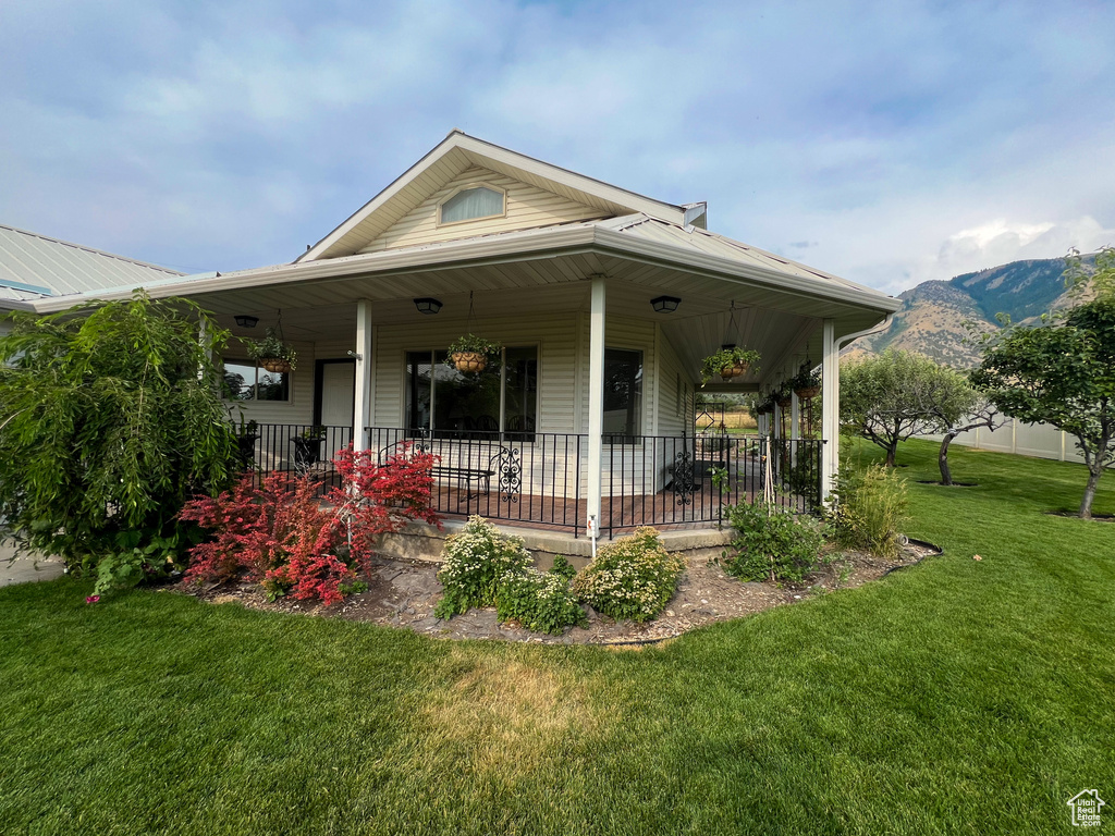 View of front facade featuring a mountain view, a front yard, and covered porch