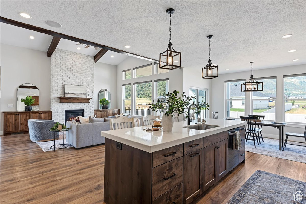 Kitchen with dark hardwood / wood-style floors, a fireplace, vaulted ceiling with beams, and sink