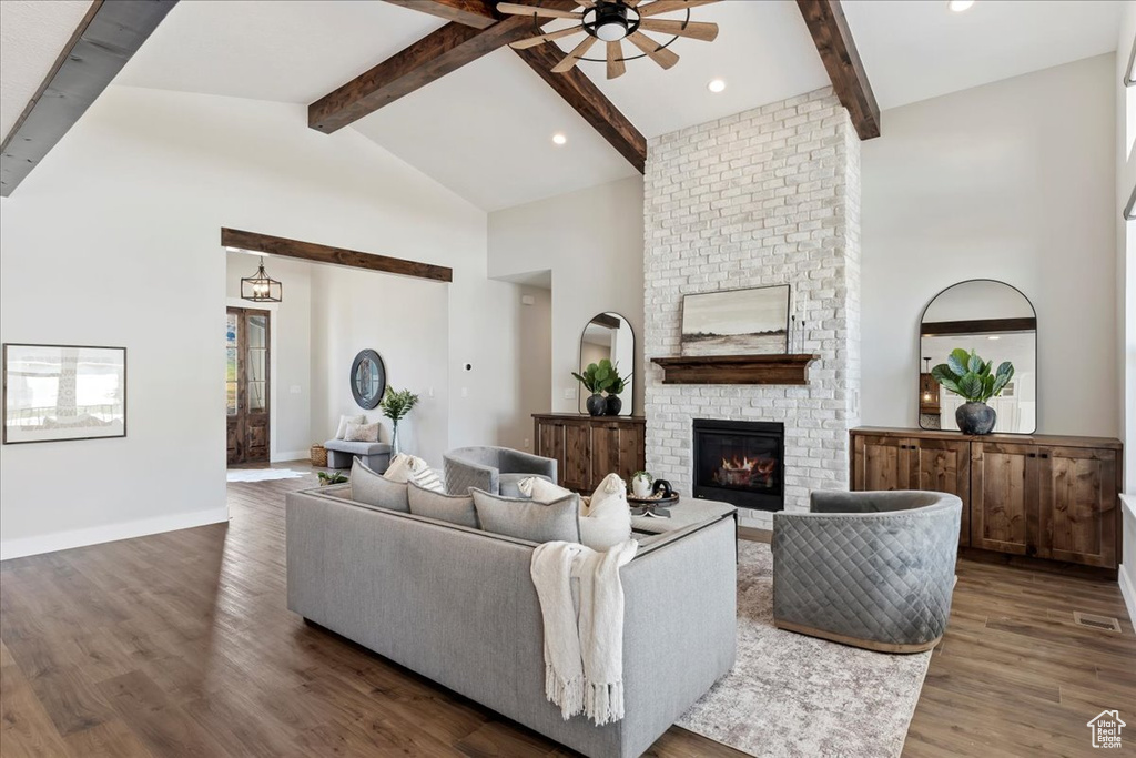 Living room with beamed ceiling, dark hardwood / wood-style flooring, a brick fireplace, high vaulted ceiling, and ceiling fan