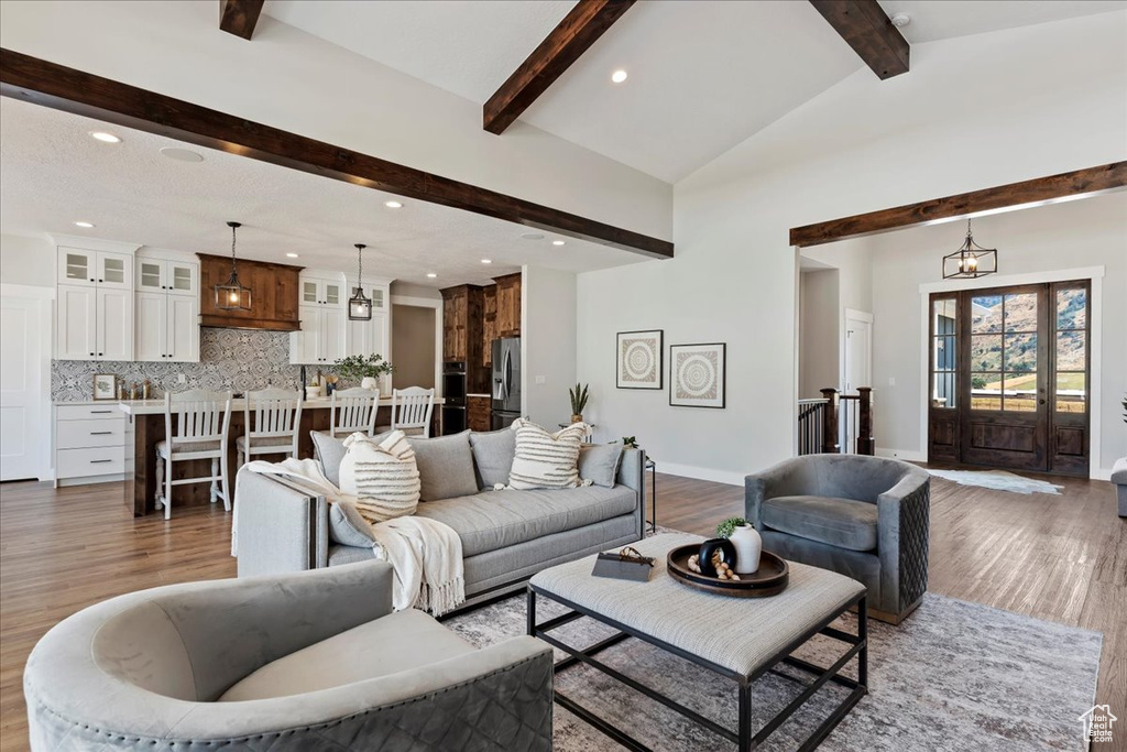 Living room featuring lofted ceiling with beams, an inviting chandelier, and hardwood / wood-style flooring