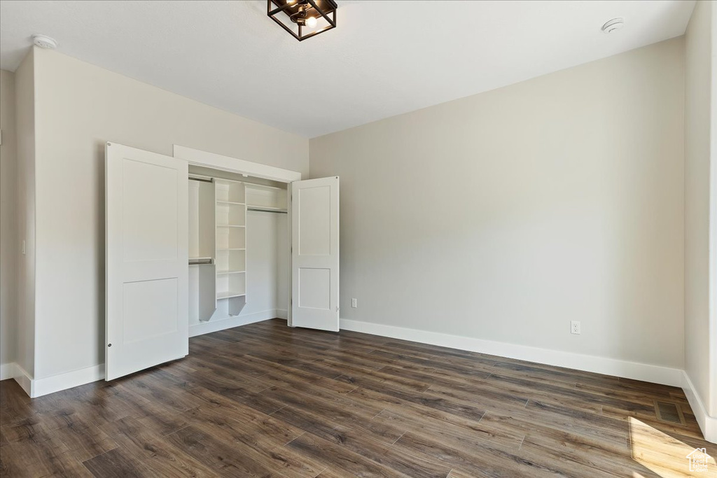 Unfurnished bedroom with a closet and dark hardwood / wood-style floors