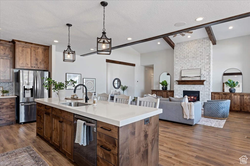 Kitchen with dark hardwood / wood-style floors, stainless steel appliances, sink, and a fireplace