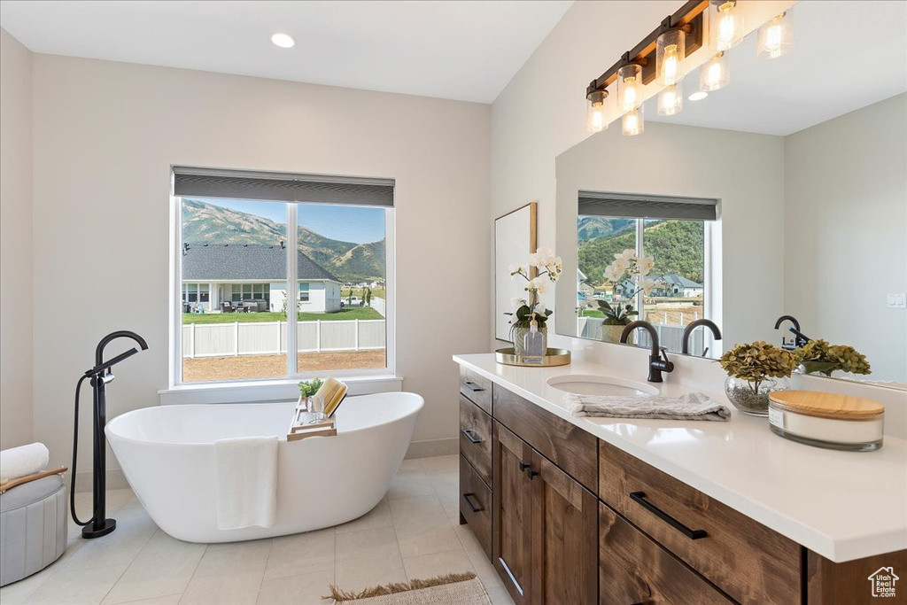 Bathroom with dual vanity, tile patterned floors, a bathing tub, and a wealth of natural light