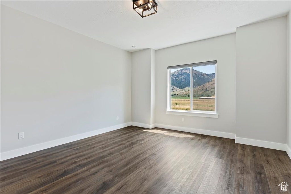 Spare room with dark wood-type flooring and a mountain view