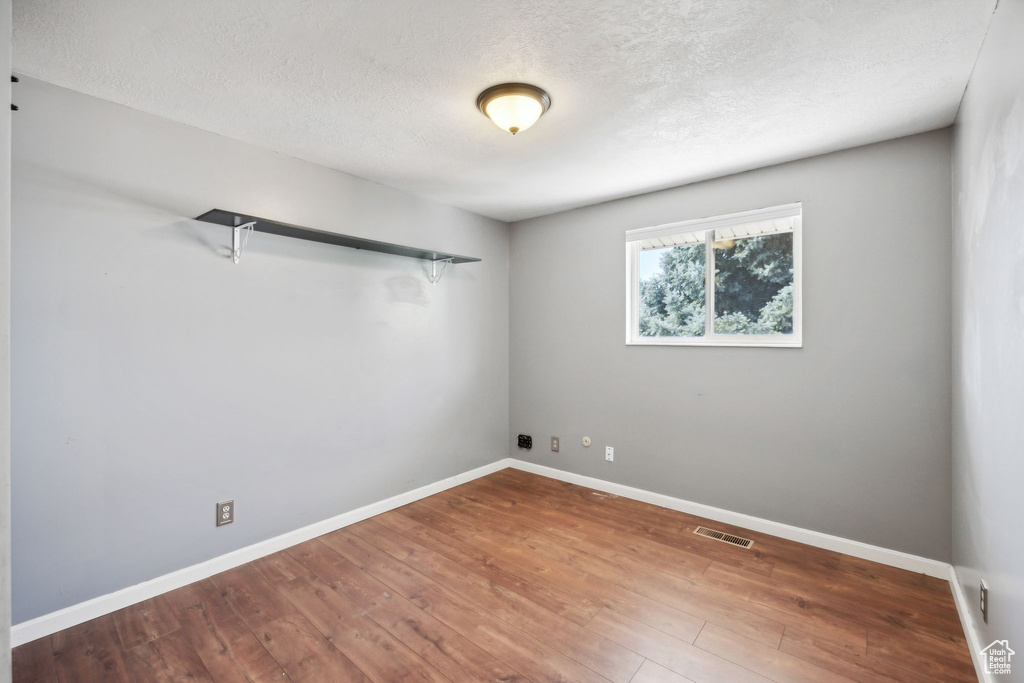 Empty room with hardwood / wood-style flooring and a textured ceiling