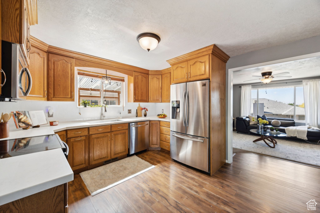 Kitchen featuring a textured ceiling, appliances with stainless steel finishes, hardwood / wood-style flooring, sink, and ceiling fan