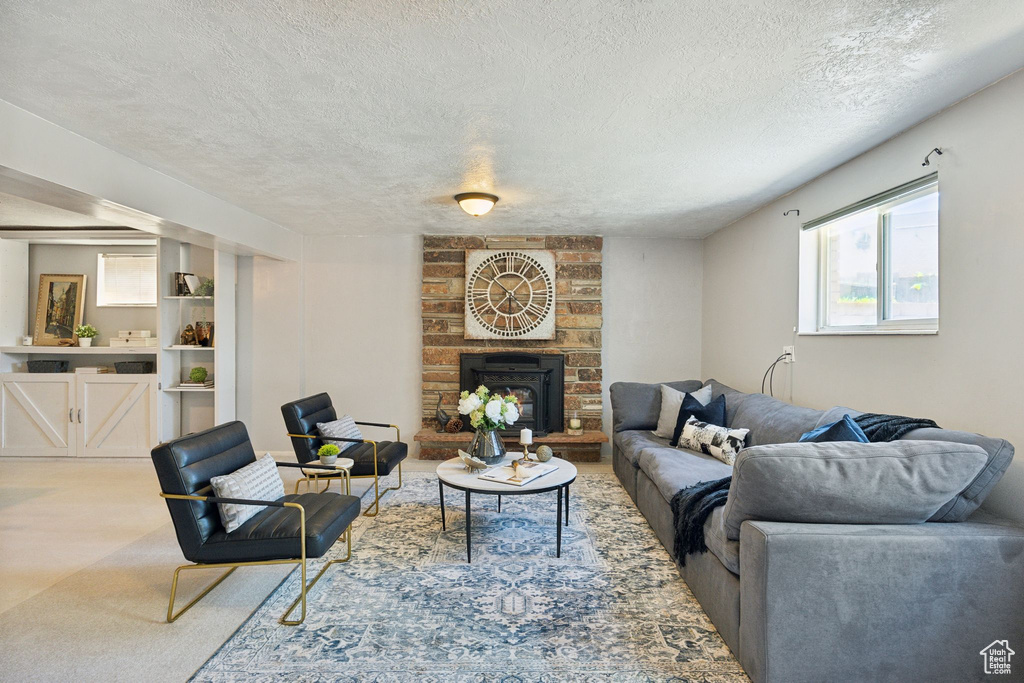 Carpeted living room featuring brick wall, a brick fireplace, and a textured ceiling