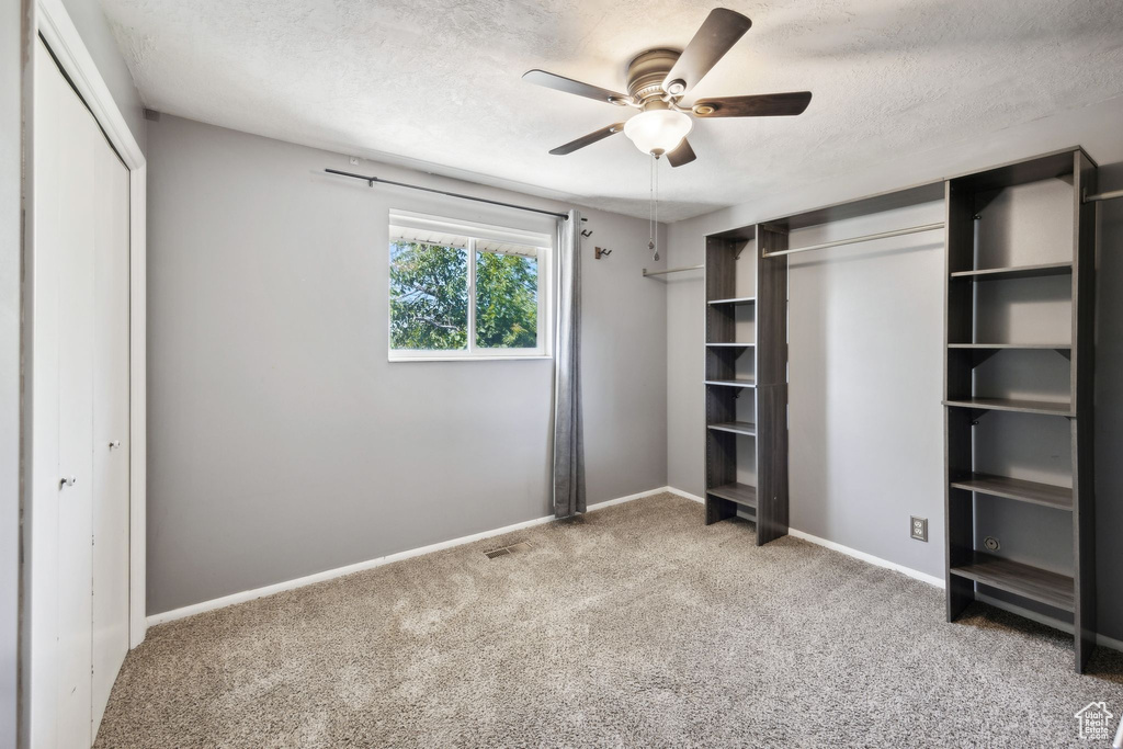 Unfurnished bedroom featuring a textured ceiling, carpet floors, and ceiling fan