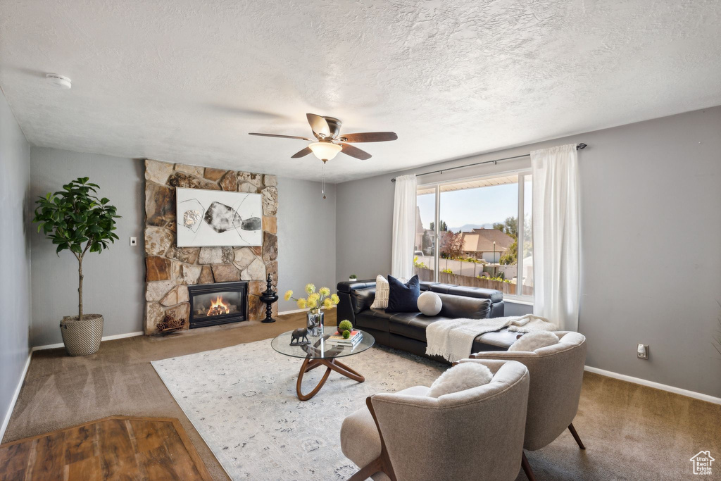 Living room with a textured ceiling, a fireplace, carpet, and ceiling fan