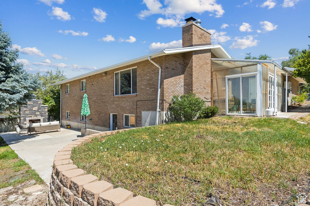 Back of property with a yard, an outdoor stone fireplace, and a patio area