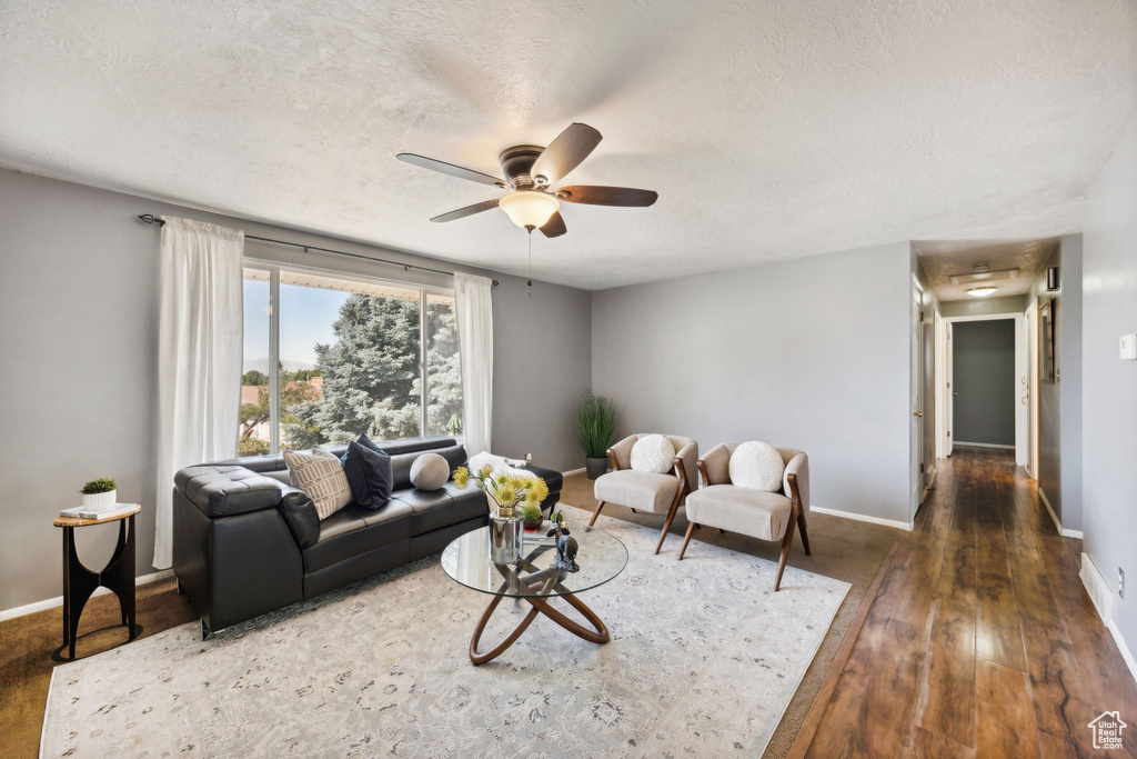 Living room with a textured ceiling, ceiling fan, and dark hardwood / wood-style flooring