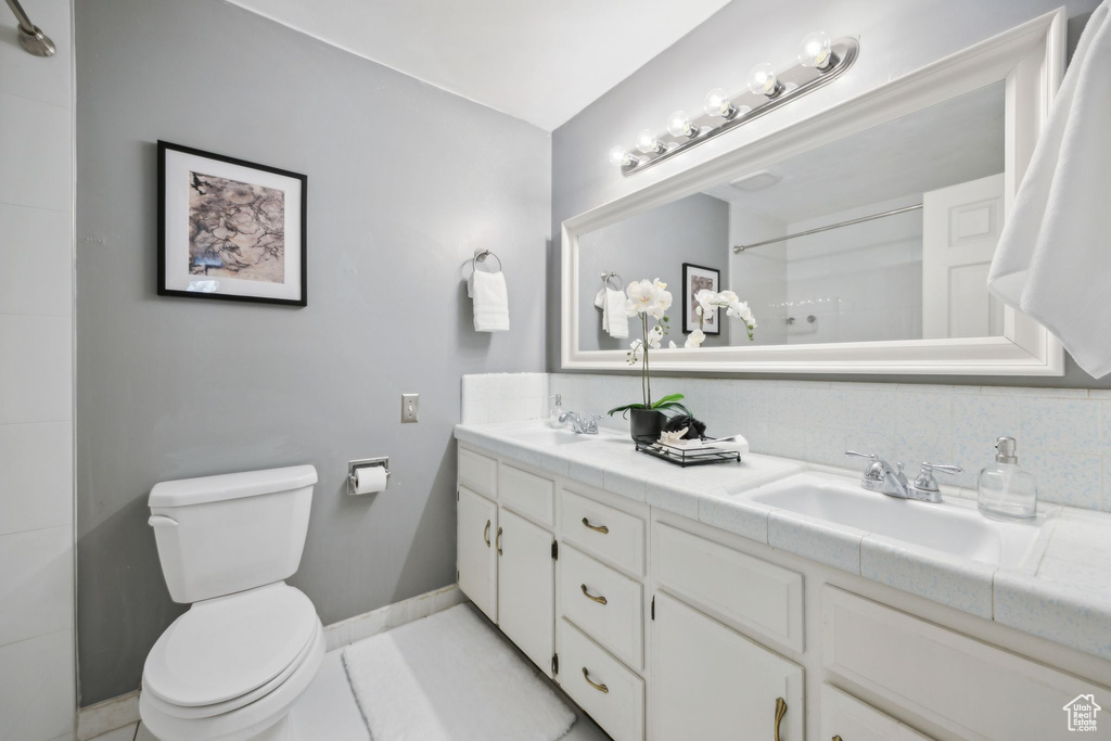 Bathroom with tile floors, double vanity, and toilet