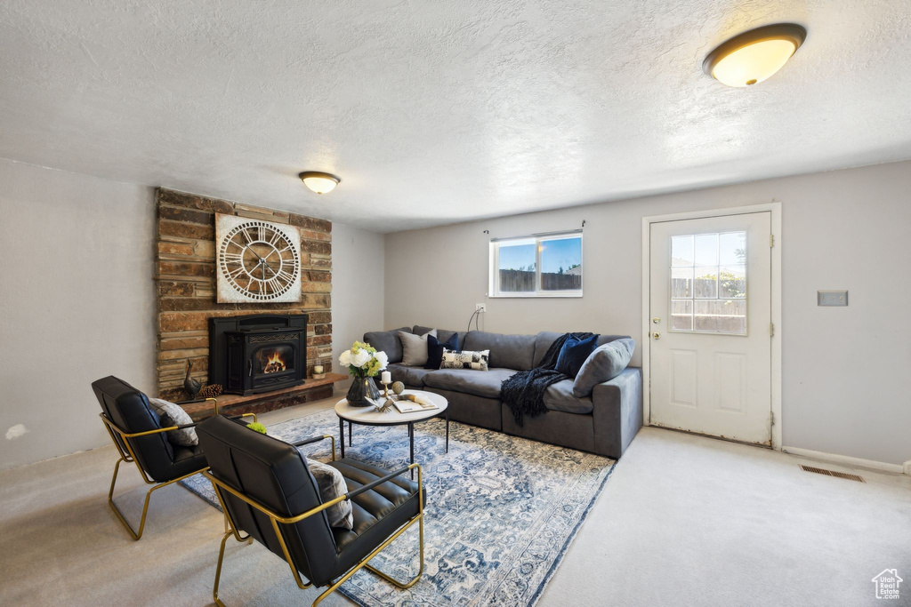 Living room featuring light colored carpet, a brick fireplace, brick wall, and a textured ceiling