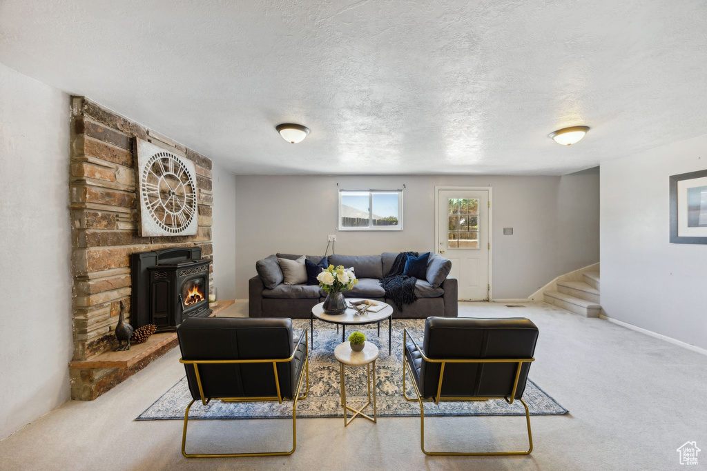 Carpeted living room with a textured ceiling, brick wall, and a wood stove