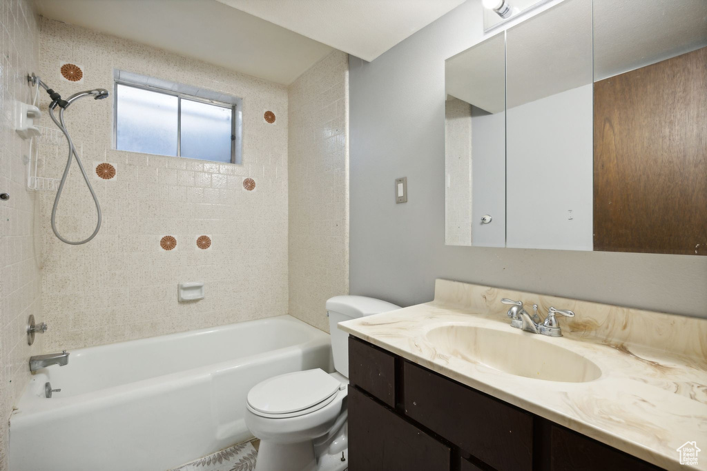 Full bathroom featuring tiled shower / bath combo, vanity, and toilet