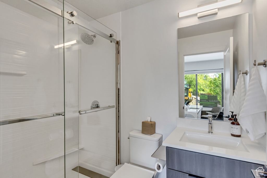 Bathroom with vanity, walk in shower, and toilet