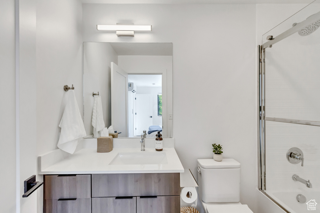 Full bathroom featuring vanity, enclosed tub / shower combo, and toilet