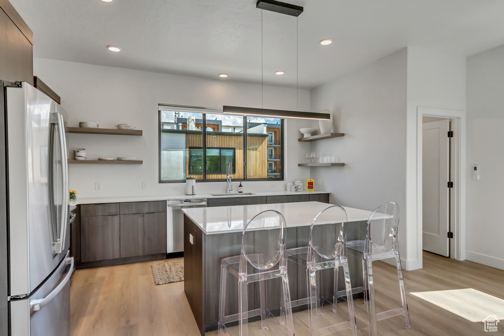 Kitchen with stainless steel appliances, light hardwood / wood-style floors, a breakfast bar area, and sink