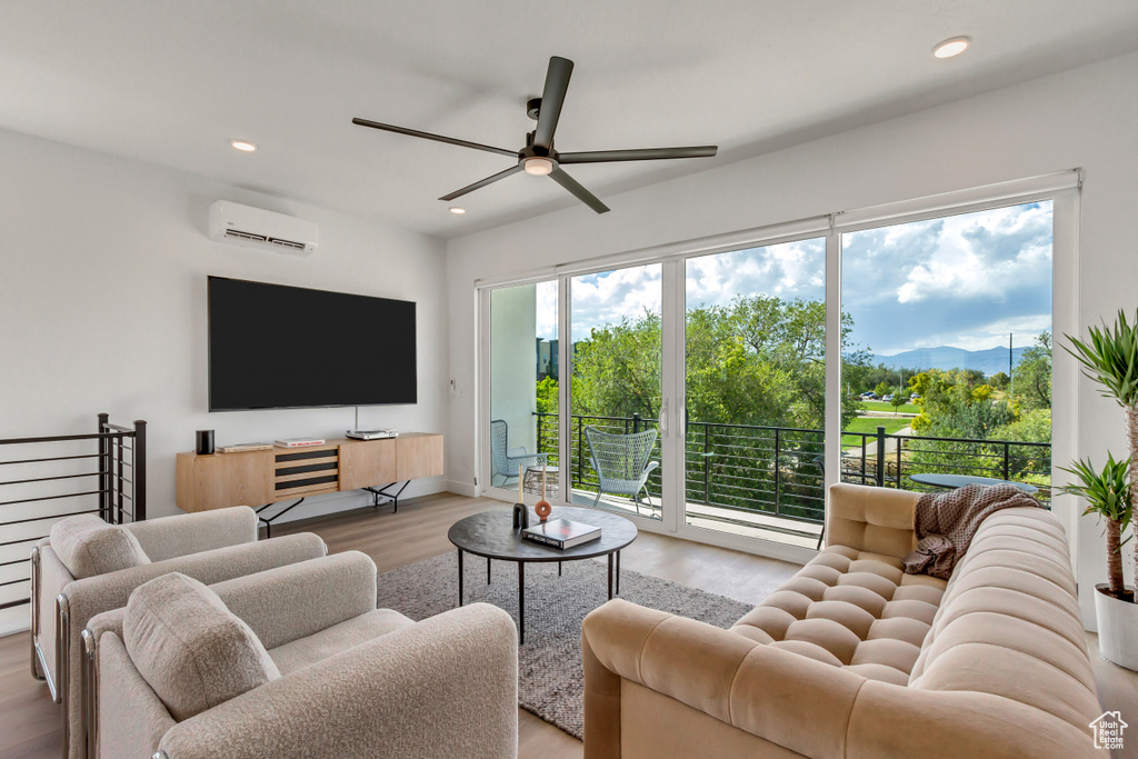 Living room featuring light hardwood / wood-style flooring, an AC wall unit, and ceiling fan